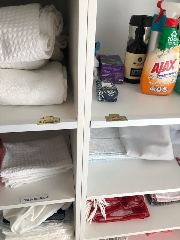 Cupboard shelves stocked with towels, linen and cleaning products