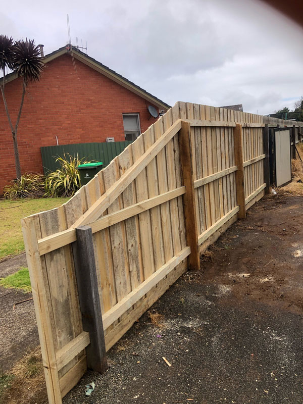 New timber paling fence, rail side, beside a red brick house