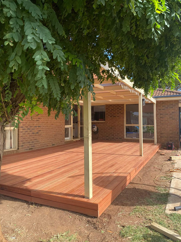 New timber deck and pergola beside a brick house, under a tree