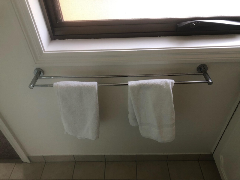 Chrome double towel rail with two white hand towels below a window
