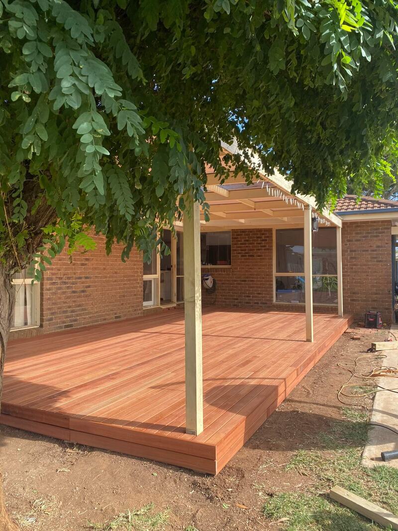 New timber deck and pergola beside a brick house, under a tree