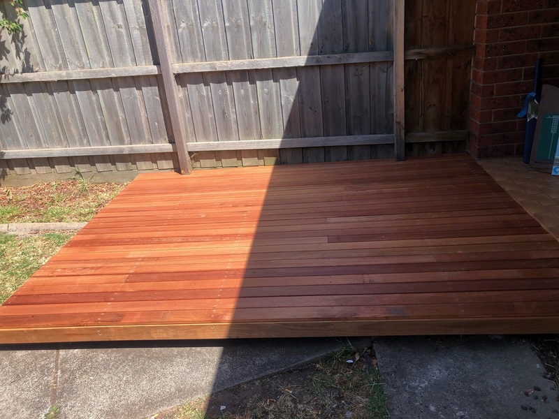 New hardwood deck in a backyard corner against a paling fence