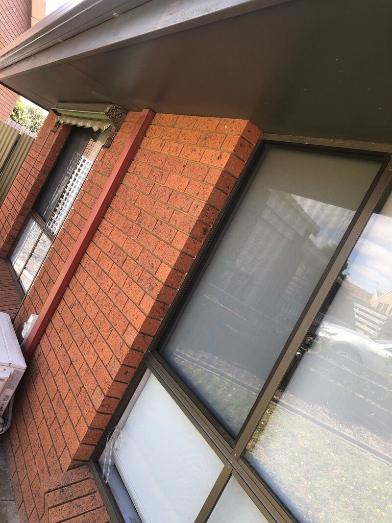 Aluminium-framed windows on a red brick house, seen from below