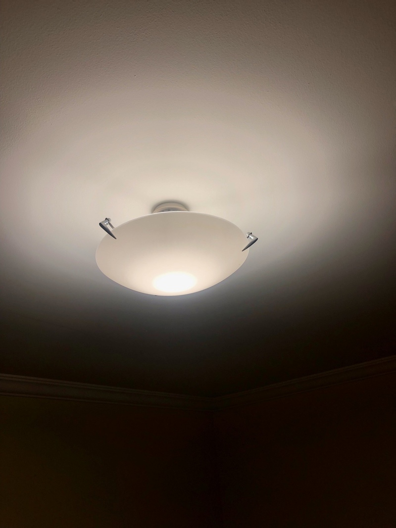 Ceiling light fitting with a frosted glass shade, switched on
